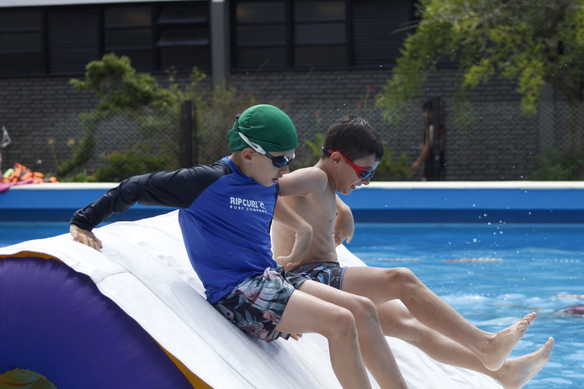 Chicos se deslizan hacia la pileta en un inflable